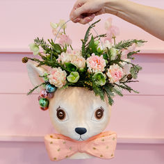 a stuffed animal with flowers in it's head is being held by a person