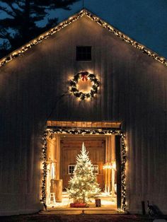 a christmas tree is lit up in front of a barn