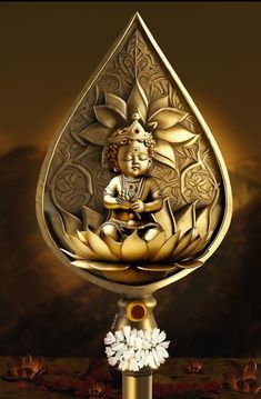 a golden buddha statue sitting on top of a water drop with flowers in front of it