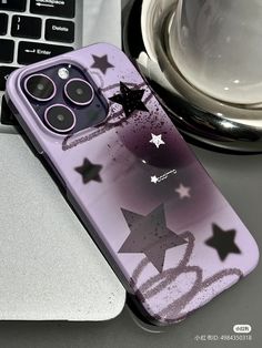 an iphone case with stars on it sitting next to a laptop and coffee mugs