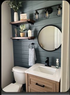 a bathroom with a toilet, sink and shelves on the wall next to a mirror