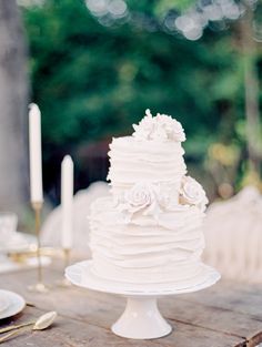 a white wedding cake sitting on top of a wooden table