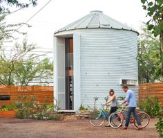 a man and woman riding bikes in front of a silo with a water tank behind them