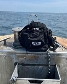 a black bag sitting on top of a metal container in the ocean next to water