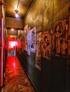 a long hallway with posters on the wall and red light coming from behind it in an industrial building