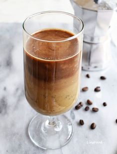 a glass filled with liquid next to coffee beans