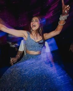 a woman in a blue dress is dancing with her arms outstretched and hands raised above her head