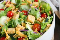 a salad with croutons, lettuce, tomatoes and cucumbers