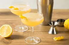 two glasses filled with lemonade sitting on top of a wooden table