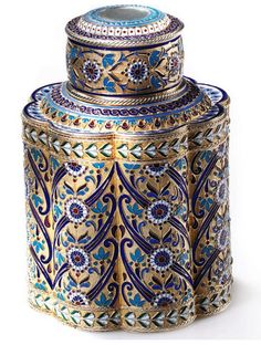 an ornate blue and gold jar with lid sitting on a white surface, next to another item