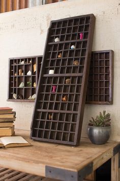 a wooden table topped with lots of books next to a shelf filled with small objects