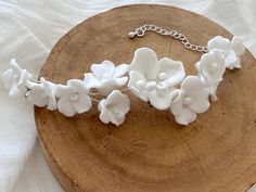 a white flower bracelet sitting on top of a piece of wood