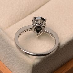 a diamond ring sitting on top of a white cushion in a box with its lid open