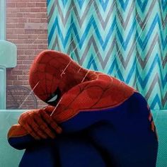 a spider man sitting on top of a blue couch in front of a brick wall