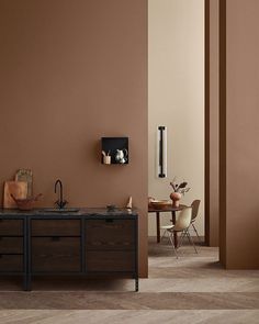 a kitchen with brown walls and wooden cabinets in the center, along with a dining room table