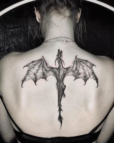 a woman's back with a dragon tattoo on it