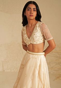 Featuring a beautiful cream lehenga made from shimmering metallic organza fabric, creating an ethereal glow. This elegant set comes with a matching blouse featuring delicate aari hand embroidery, adding a touch of intricate detail. A flowing silk organza dupatta completes the look, draped softly to highlight the outfit's timeless grace. Ideal for a reception at a destination wedding, this ensemble captures the heart with its simple beauty and elegance. Composition : Lehenga, Blouse, Dupatta - Organza Care: Dry Clean Only and Vacuum Storage This product can be customized for sleeves, length of blouse and neckline Delivery : 4-6 weeks as the product is hand crafted. Check Size Guide or choose MySize for free customisation (All Sizes above XL can be made at 15% additional cost) For more infor Elegant Embroidered Cream Lehenga, Elegant Beige Choli With Intricate Embroidery, Elegant Cream Choli For Festive Occasions, Elegant Cream Choli For Festive Season, Elegant Organza Lehenga With Unstitched Blouse, Elegant Beige Choli With Sheer Dupatta, Cream Organza Sets With Intricate Embroidery, Party Wear Cream Sharara With Resham Embroidery, Festive Beige Georgette Lehenga