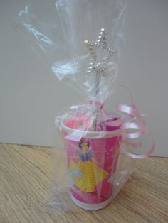 a plastic cup filled with candy and wrapped in cellophane on top of a wooden table