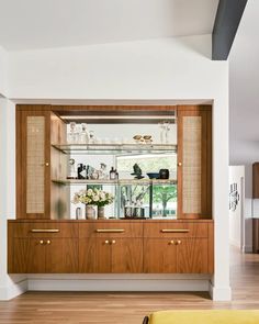 a wooden cabinet with glass shelves and vases on it's sides in a living room