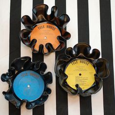 three black and yellow records sitting on top of a striped tablecloth with white stripes