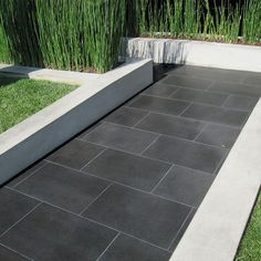 an outdoor area with black tiles and grass