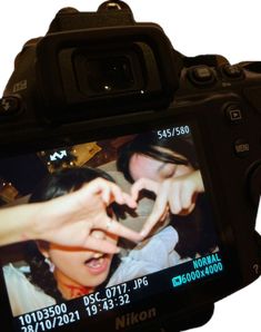 a person making a heart sign with their hand on a digital camera's screen