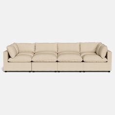 a beige sectional couch with pillows on the top and bottom, in front of a white background