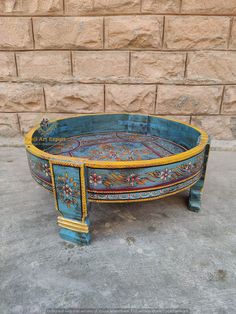 an old blue and yellow painted tray with flowers on the bottom, sitting in front of a brick wall