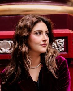 a woman with long hair sitting in front of a red box and looking off to the side