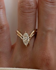 a woman's hand with a diamond ring on top of her finger, and the other hand holding an engagement ring