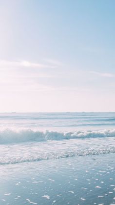 a person walking on the beach carrying a surfboard