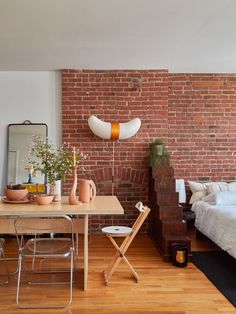 a room with a brick wall and wooden flooring in the corner, along with a bed