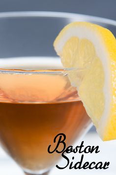 a close up of a drink in a glass with a slice of lemon on the rim