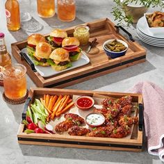 two trays filled with food on top of a table next to plates and glasses