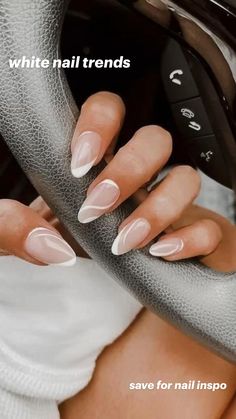 a woman's hand with white and pink nail polish on her nails holding the steering wheel