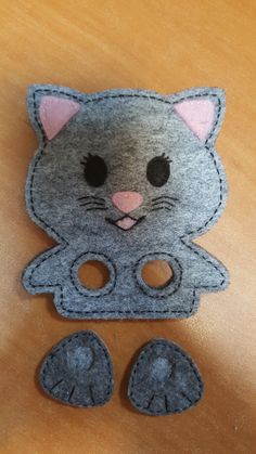 a felt cat with two holes in the middle and one hole cut out to look like it is sitting on a table