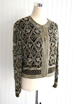 "This is a VERY heavily beaded cocktail party jacket.  There are some missing pearls along the neckline and down the front.   It is otherwise in beautiful conditon.  Marked size L 44\" total bust 17\" shoulder  19 1/2\" nape to hem  Purveyor's Note: We have searched far and wide, wrestled bears, braved the cold, traversed mountain ranges, fought pirates, swam with sharks and eaten at many a questionable road side taco stand to provide our customers with one of a kind vintage pieces.  Know that whichever piece you choose to make your own has its own story and has traveled through time to get to you.  Though we strive to provide the absolute best, \"pristine\" vintage pieces are rare birds, if not altogether non-existent.  That being said, please understand that part of buying and wearing vi Elegant Embellished Festive Outerwear, Elegant Hand Embellished Long Sleeve Outerwear, Elegant Long Sleeve Hand Embellished Outerwear, Elegant Fitted Hand-embellished Outerwear, Elegant Fitted Hand Embellished Outerwear, Elegant Embroidered Party Outerwear, Embellished Long Sleeve Silk Outerwear, Elegant Embroidered Evening Outerwear, Silk Sequined Long Sleeve Outerwear