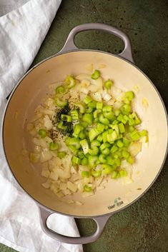 onions and celery are being cooked in a pan on the stove top next to a napkin