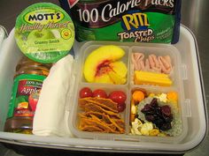 an open lunch box with fruit, crackers and yogurt on the side