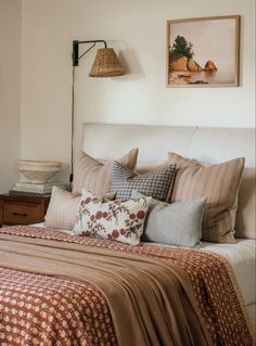 a bed with lots of pillows on top of it and a lamp next to it