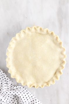 an uncooked pie crust next to a polka dot napkin on a marble surface