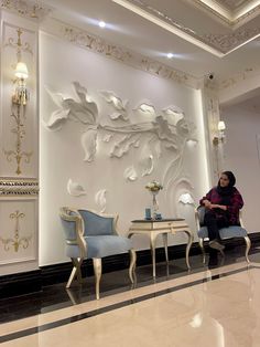 a woman sitting on a chair in front of a wall