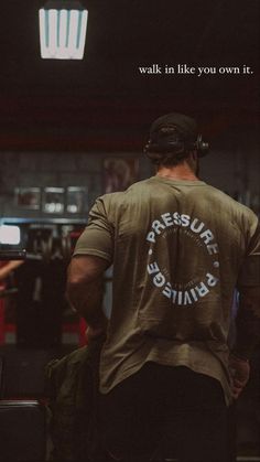 a man with a back pack walking through a train station while wearing a t - shirt that reads pressure grinds