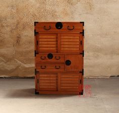 a wooden cabinet with four drawers and two doors on each side, in front of a wall