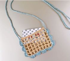 a crocheted purse is hanging on a blue string and has buttons in it