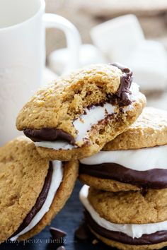 cookies with chocolate and marshmallows are stacked on top of each other next to a cup of coffee