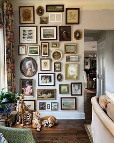 a living room filled with lots of framed pictures on the wall next to a couch