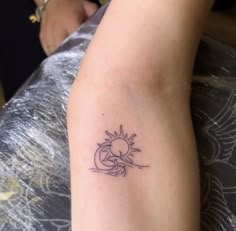 a woman's arm with a small sun tattoo on the left side of her arm