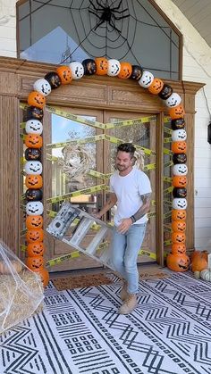 a man holding a large box in front of a door decorated with pumpkins and jack - o'- lanterns