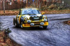 a yellow and black car driving down a dirt road